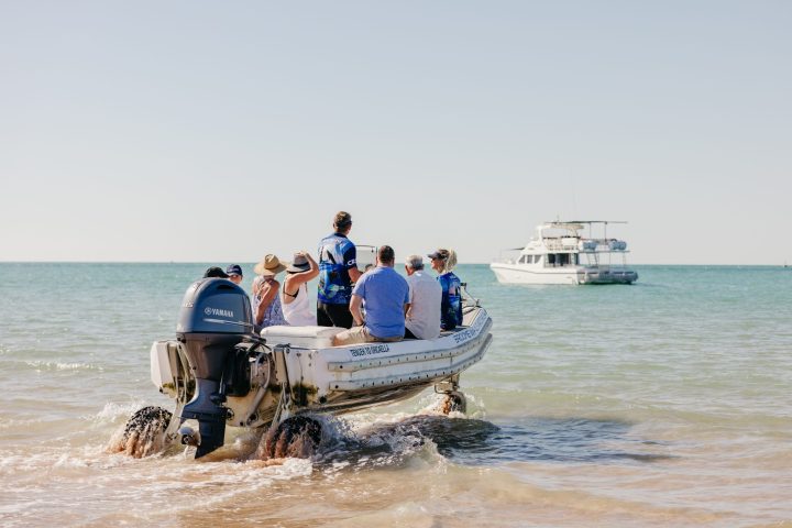 a group of people riding on the back of a boat in the water