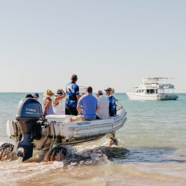 a group of people riding on the back of a boat in the water